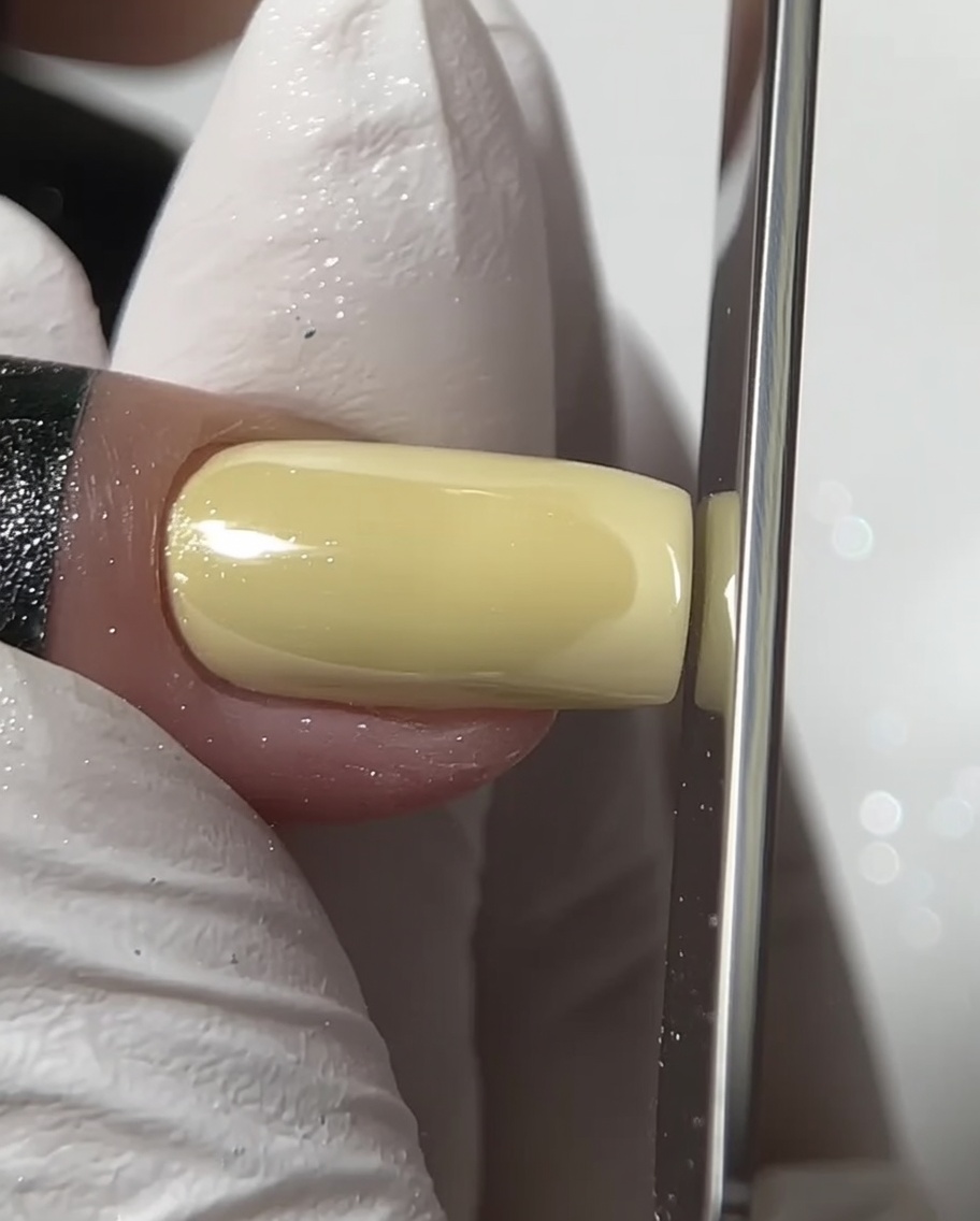 Eine Nagelfeile formt die freie Kante eines quadratischen Chrom-Nagels.