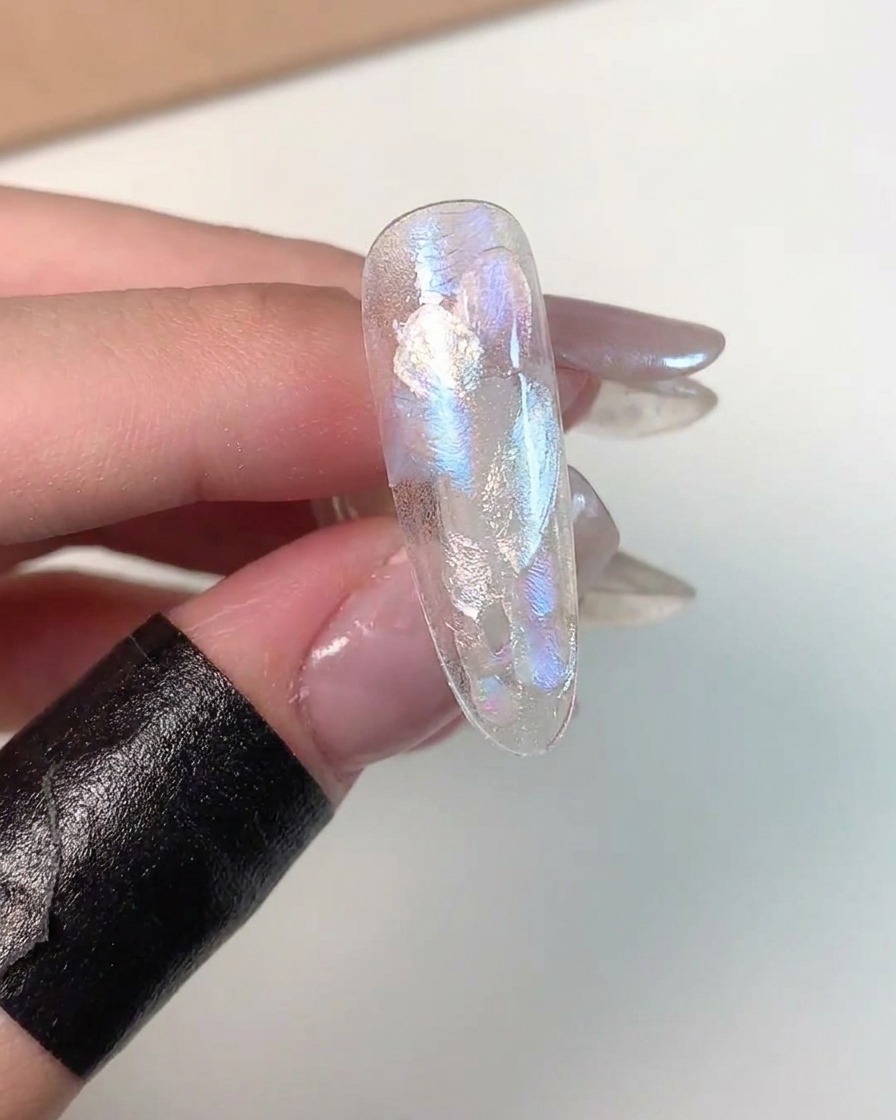 Eine Nahaufnahme zeigt Cat-Eye-Gel, das in der unteren Ecke einer Übungs-Nagelspitze magnetisiert wird.