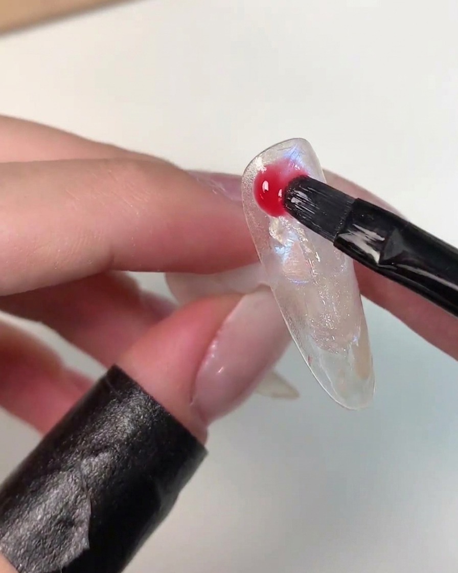 Ein Pinsel trägt lebendiges Eiko Esaka Farbgel zufällig über die Nail-Art-Oberfläche auf.