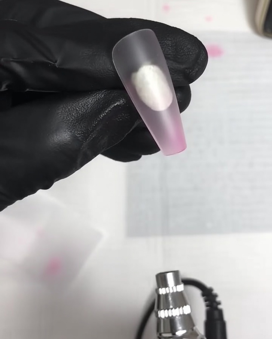 Ein klarer matter Nageltip zeigt einen weichen, hellrosa Nebelverlauf an seinem unteren Rand über einer Airbrush.