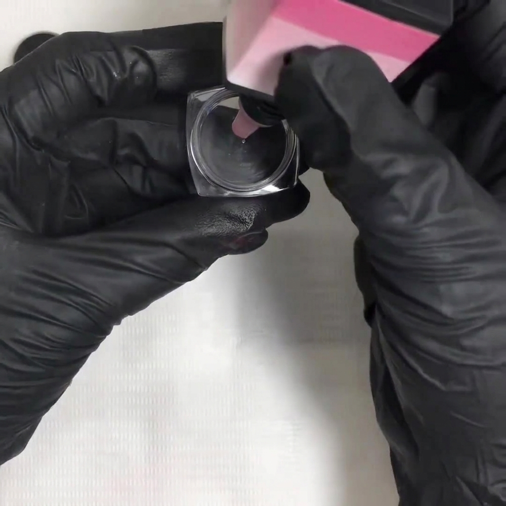 Aus einer Flasche tropft Gel-Lack in einen kleinen quadratischen Mischbehälter.