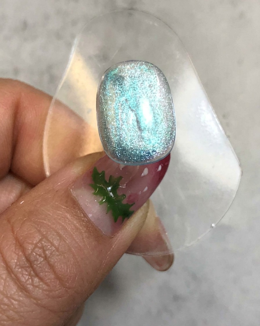 Ein Nagel befindet sich in einer Aushärtungslampe mit glühendem Licht um die transluzente blaue Geloberfläche herum.
