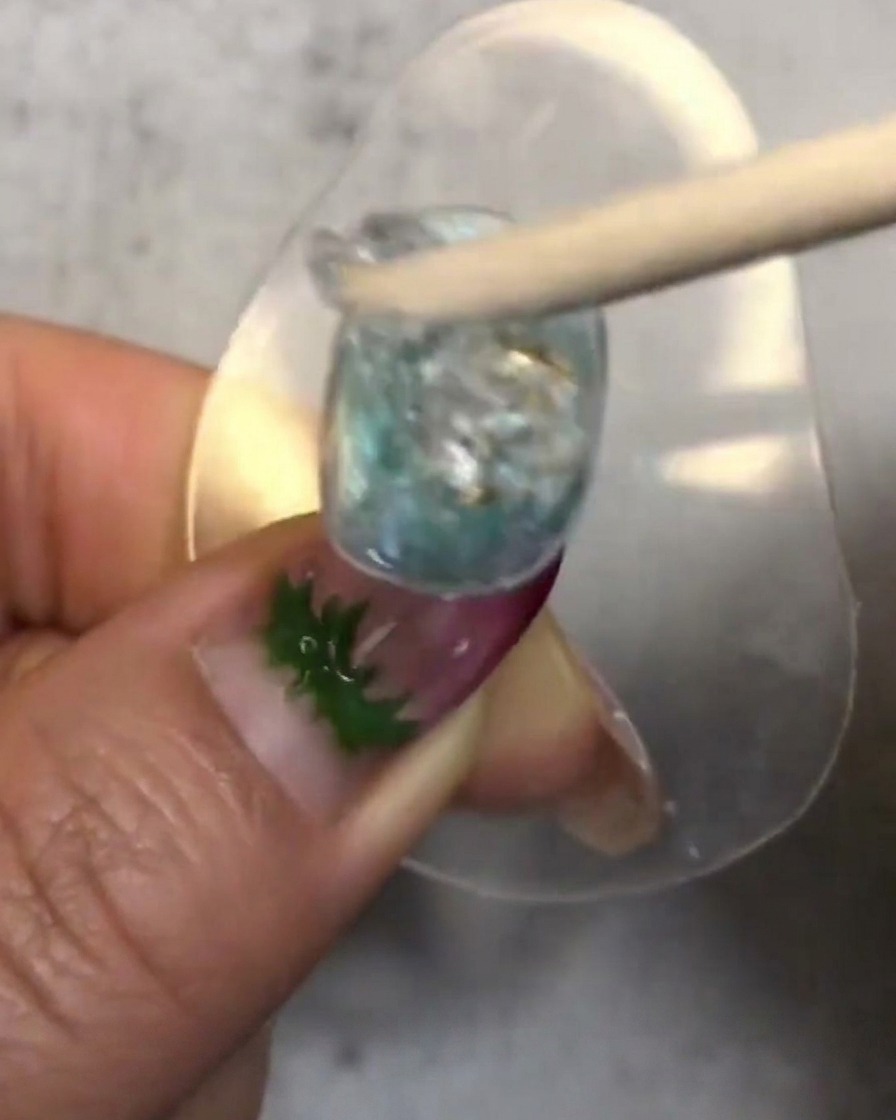 Ein Holzstäbchen rührt einen Klecks transluzentes Soft Candy Gel um und platziert ihn auf dem dekorierten Nagel.