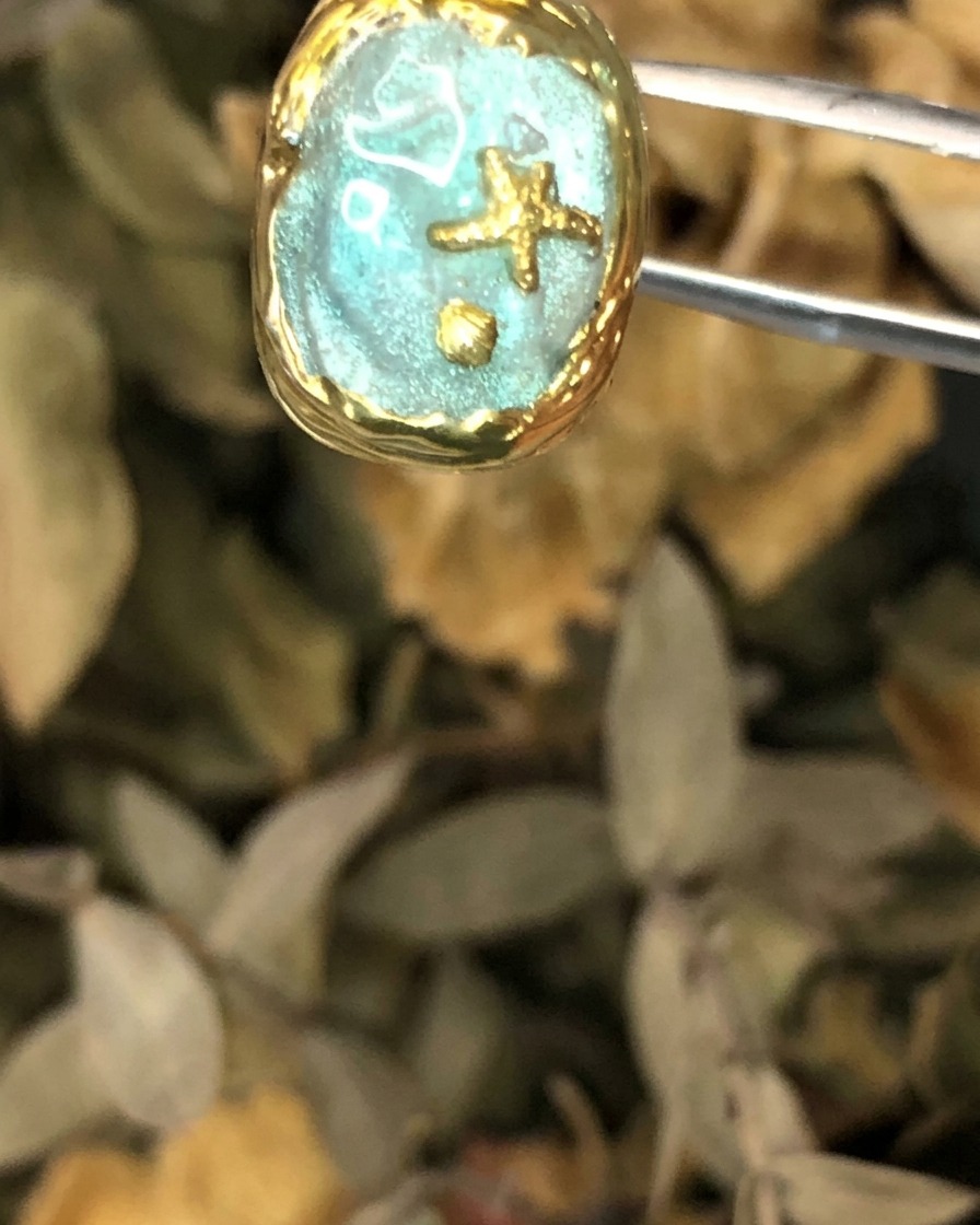Eine Nahaufnahme des fertigen Nagelkunstwerks im Atlantis-Stil, gehalten von einer Pinzette.