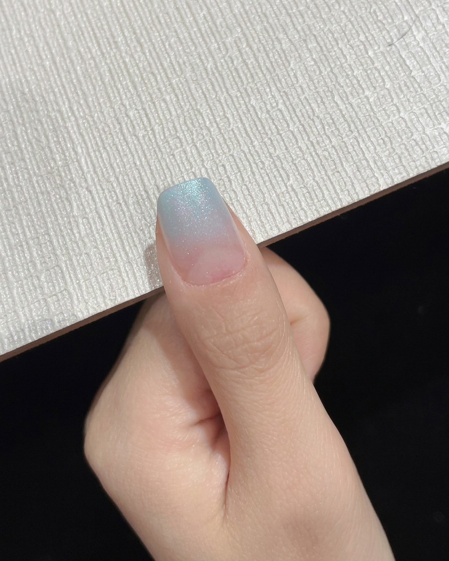 Ein fertiger blauer Gradient-Ombré-Nagel wird als Zwischenstandszustand gezeigt.