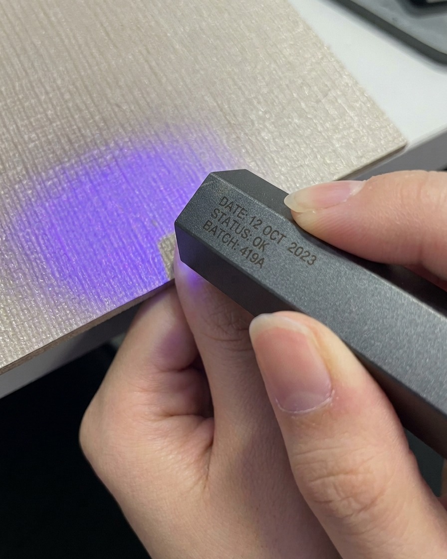 Eine Hand legt einen Daumen unter eine kompakte, graue tragbare UV-LED-Lampe.