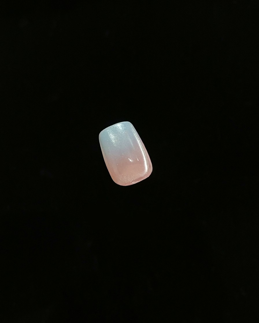 Eine Nahaufnahme eines einzelnen fertigen Nagels mit Gradient-Ombré-Effekt vor dunklem Hintergrund.