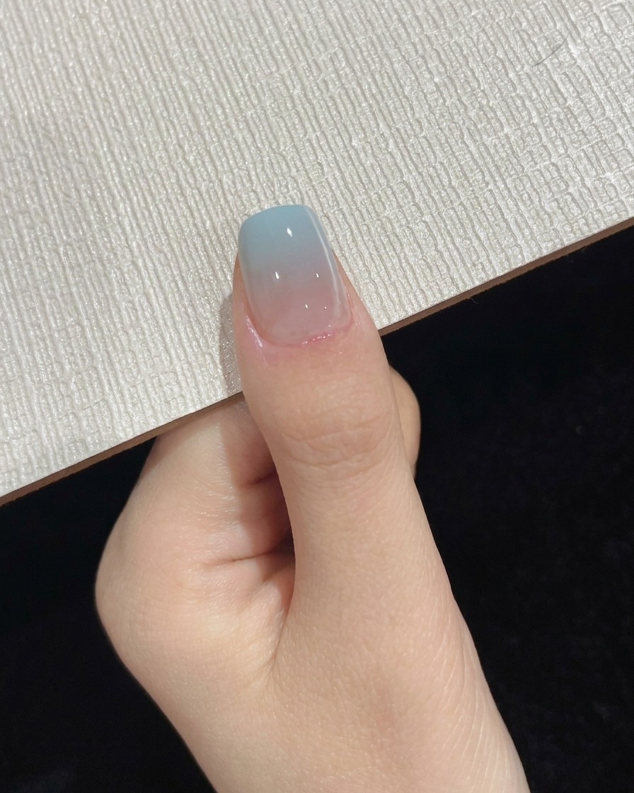 Ein Daumen befindet sich während des letzten Topcoat-Aushärtungsschritts unter einer tragbaren UV-LED-Lampe.