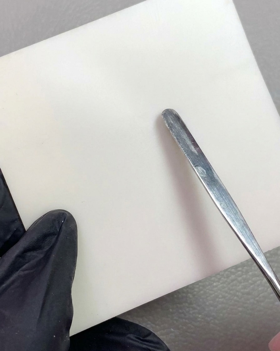 Ein Metallwerkzeug platziert ein Stück weißes Modelliergel auf einer sauberen Mischpalette.