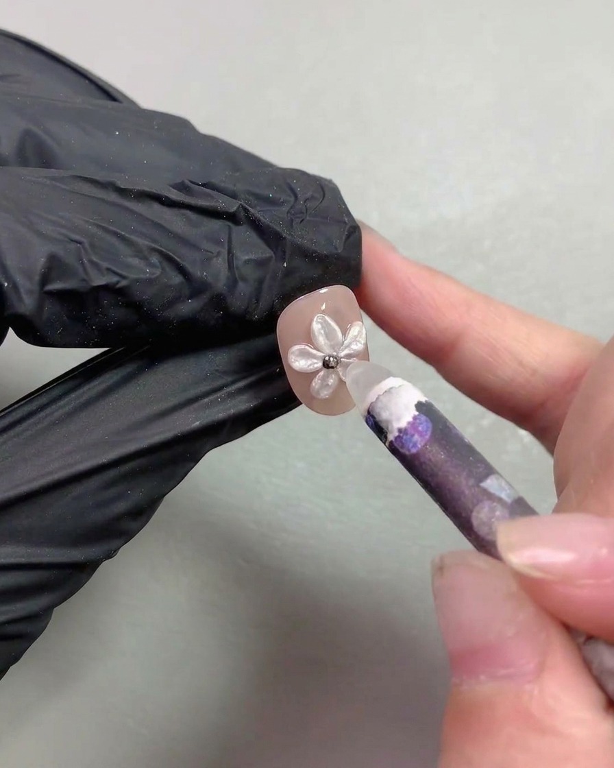 Ein Wachsstift platziert winzige metallische Stahlperlen in die Mitte der Perlenblume.