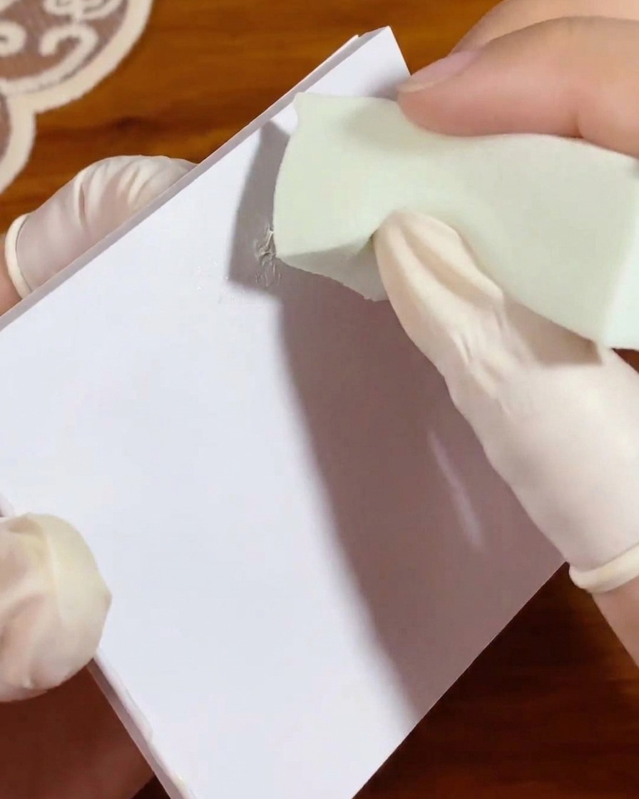 Ein kleiner grüner Make-up-Schwamm wird in einen Klecks weißes Gel auf Palettenpapier getupft, um die Farbe gleichmäßig zu verteilen.
