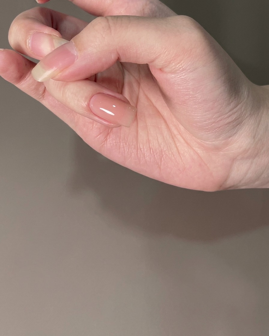 Ein Fingernagel mit einem unter Licht ausgehärteten Nude-Unterlack.