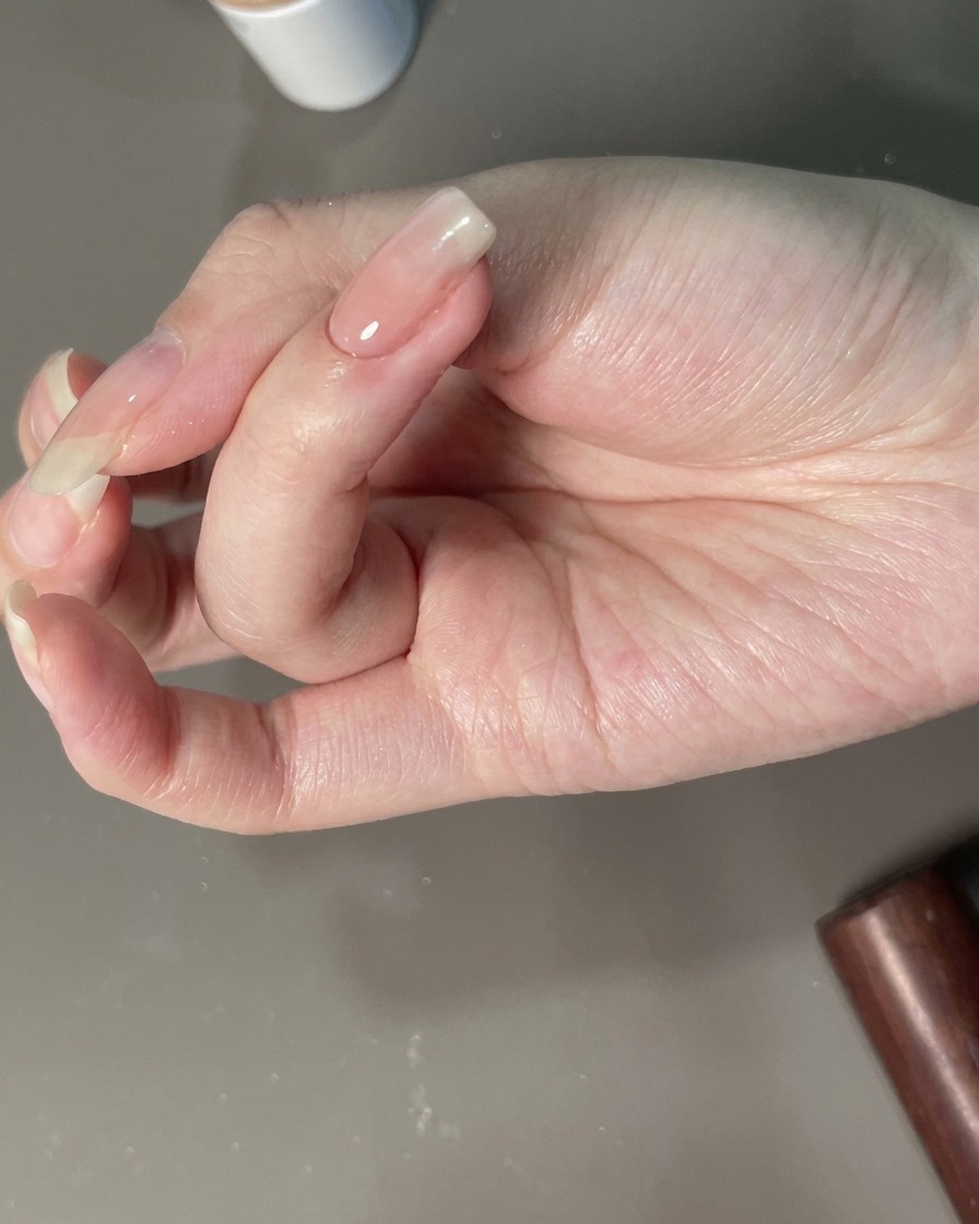 Eine Hand wird für die Endaushärtung unter eine UV-Lampe positioniert.