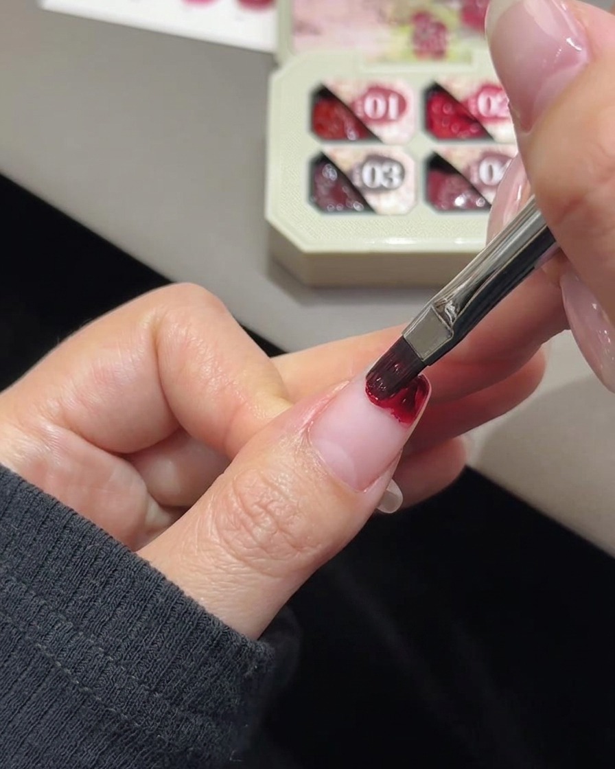 Ein kleines Make-up-Schwämmchen verblendet die roséfarbene Gel-Farbe auf einer Nagelspitze.