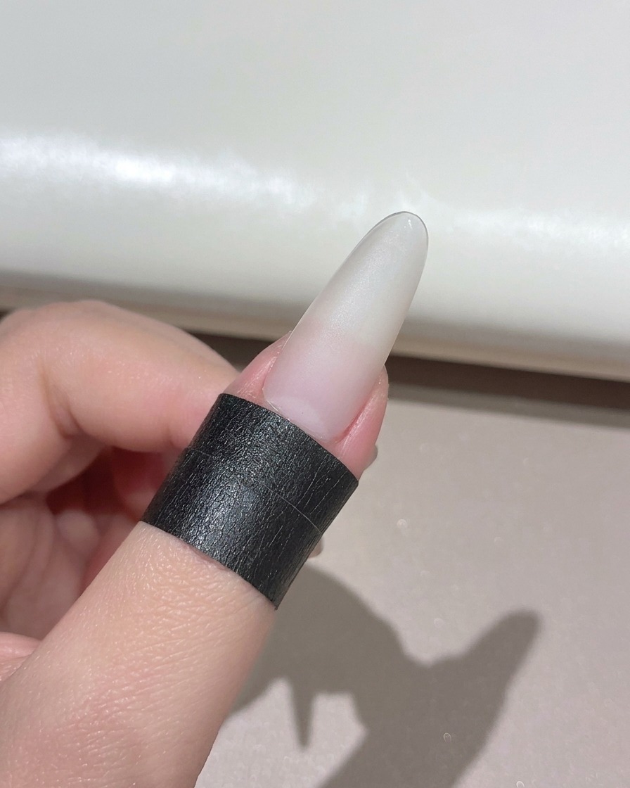 Ein manikürter Nagel wird unter einer kompakten Hand-UV-LED-Lampe positioniert.