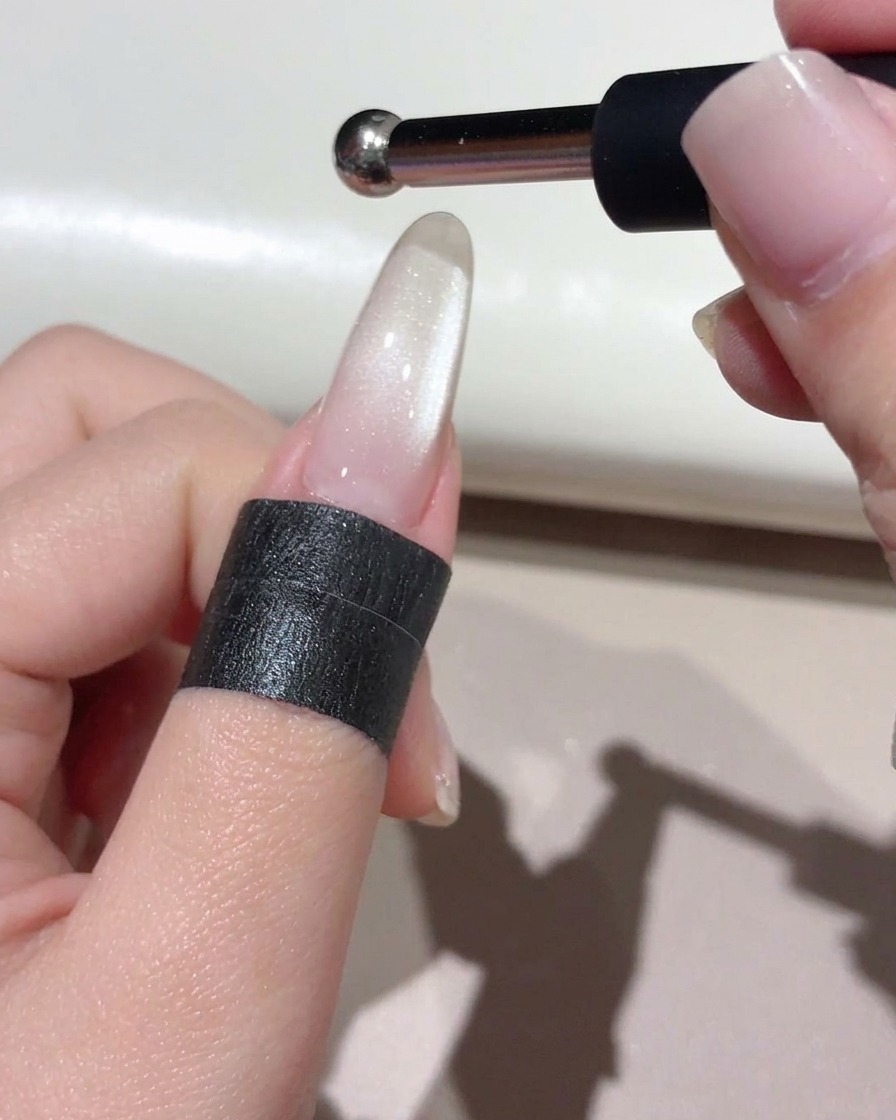 Ein kleiner Kugelpunktmagnet wird über den Nagel gehalten, um eine konzentrierte Glasperlenreflexion zu formen.