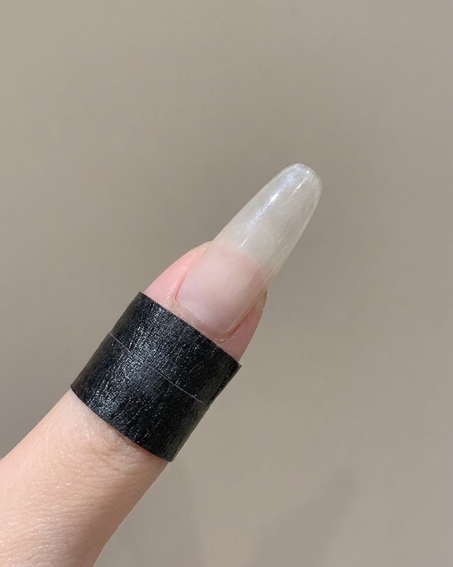 Ein Silikonwerkzeug drückt den gebogenen Rand eines French-Stickers auf einem Finger fest.