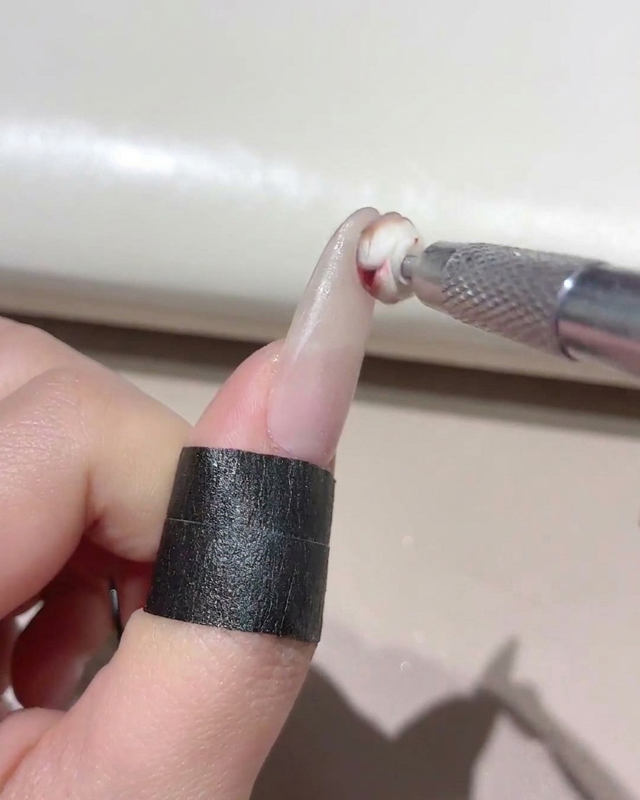 Ein kleines Schwammwerkzeug tupft gemischtes Gel auf die Spitze eines manikürten Nagels.
