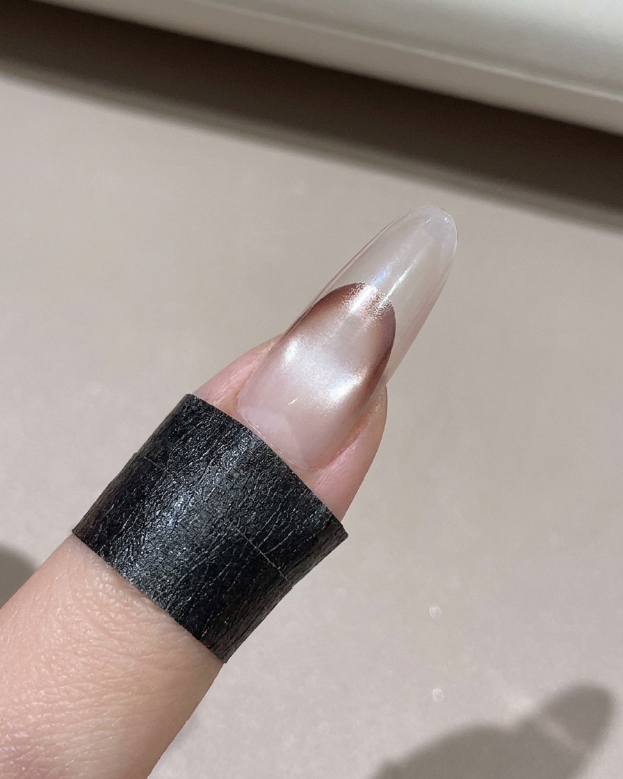 Ein fusselfreies Tuch reinigt überschüssiges Gel vom Rand eines dekorierten Nagels.