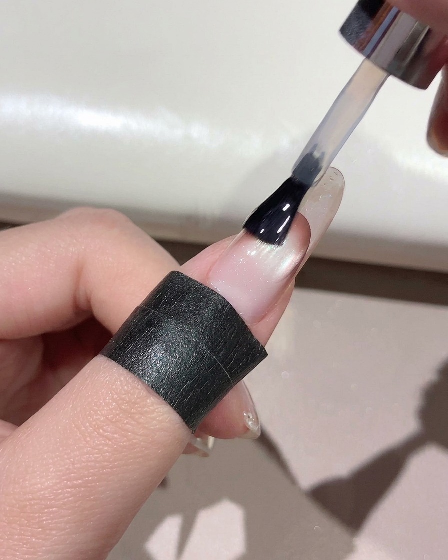 Ein Pinsel trägt klaren Top Coat über die gesamte Oberfläche eines manikürten Nagels auf.