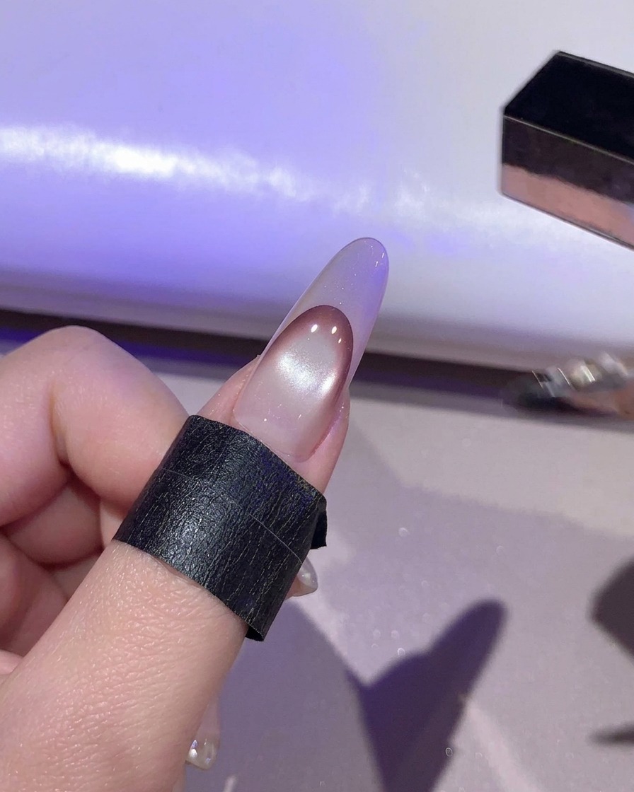 Ein Nagel härtet unter violettem Licht in einer UV/LED-Lampe aus.