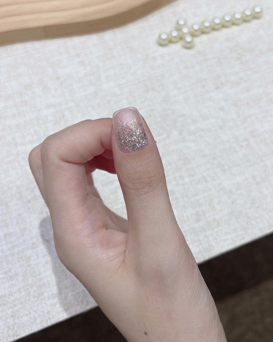 Eine Hand hält eine Flasche dunklen Gel-Nagellack mit abgenommenem Verschluss und bereitet sich auf den Auftragsschritt vor.