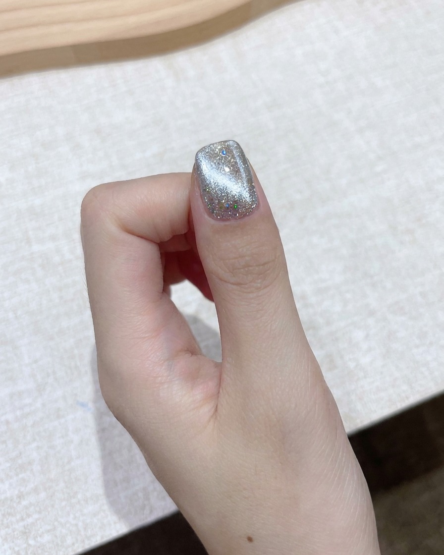 Ein rechteckiger Blockmagnet wird nahe an einen schimmernden Cat-Eye-Gelnagel gehalten, um einen hellen Aurora-Strahl zu formen.