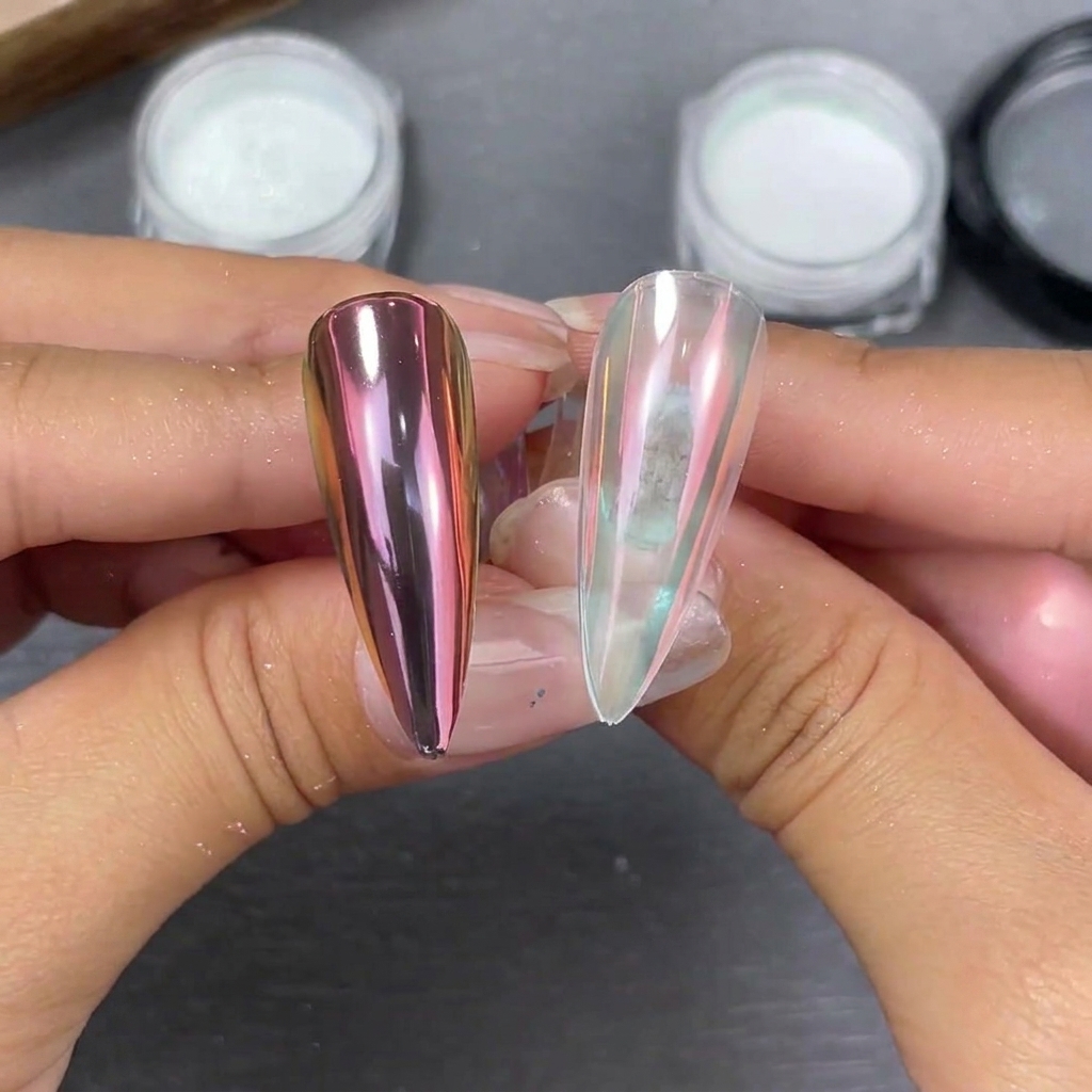 Zwei Stiletto-Nagelspitzen nebeneinander zeigen Moonlight-Pulvereffekte: eine rosa-lila Verschiebung auf einer schwarzen Base und ein weiches perlmuttartiges Leuchten auf einer klaren Base.