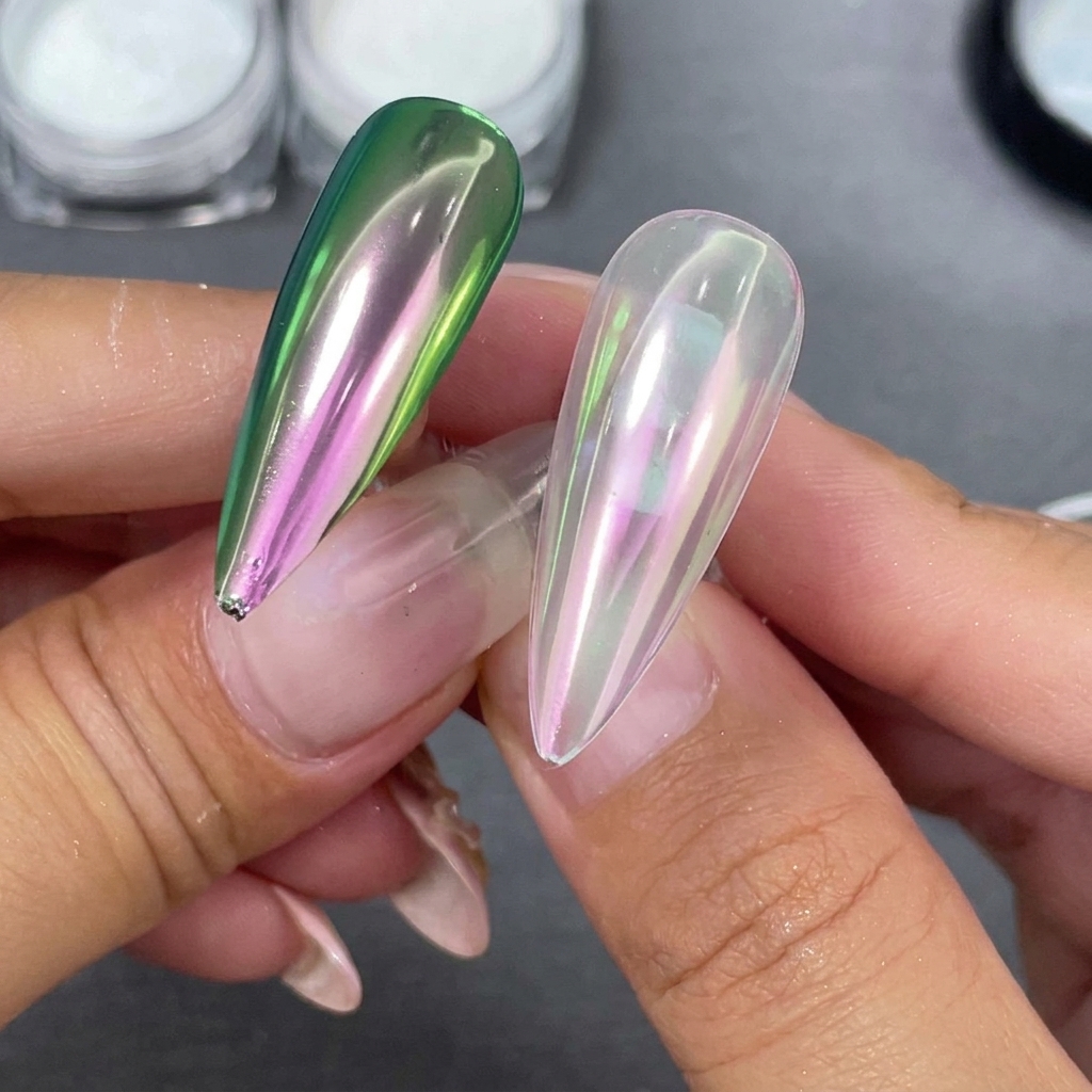 Zwei fertige Stiletto-Nagelspitzen nebeneinander gehalten, eine mit klarer Base und eine mit schwarzer Base, die eine grün-lila Verschiebung zeigen.