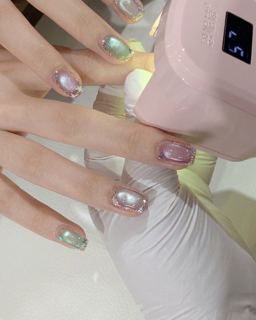 Eine Nahaufnahme der Hand einer Kundin unter einer rosa Mini-UV/LED-Nagellampe zum Aushärten.