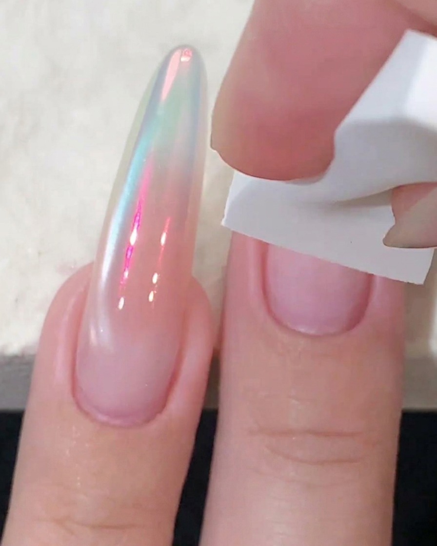 Ein weißer Schwamm tupft pinkes Blush-Gel auf die Mitte eines Fingernals, um die Farbe zu intensivieren.