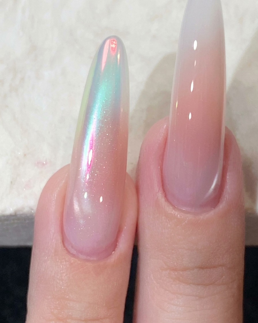 Ein starker Magnet wird nah an die Seite eines manikierten Nagels gehalten, um den magnetischen Schimmer zu formen.