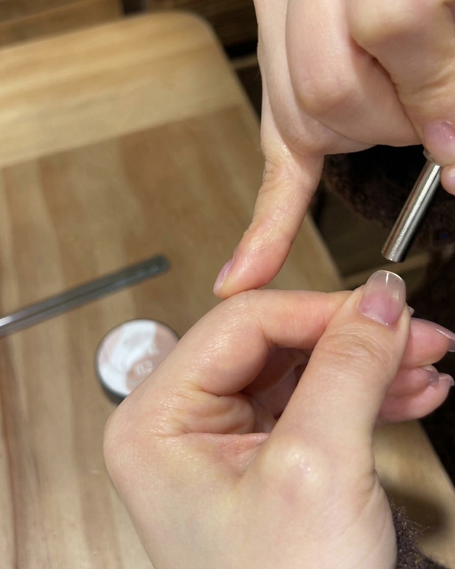 Eine tragbare weiße UV/LED-Lampe, die helles Licht auf einen Fingernagel strahlt, um die Gelschicht auszuhärten.