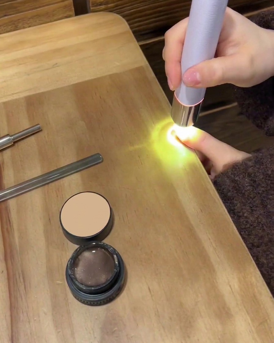Ein kleines Wattepad wischt die Oberfläche eines Nagels ab, um klebrige Rückstände zu entfernen.