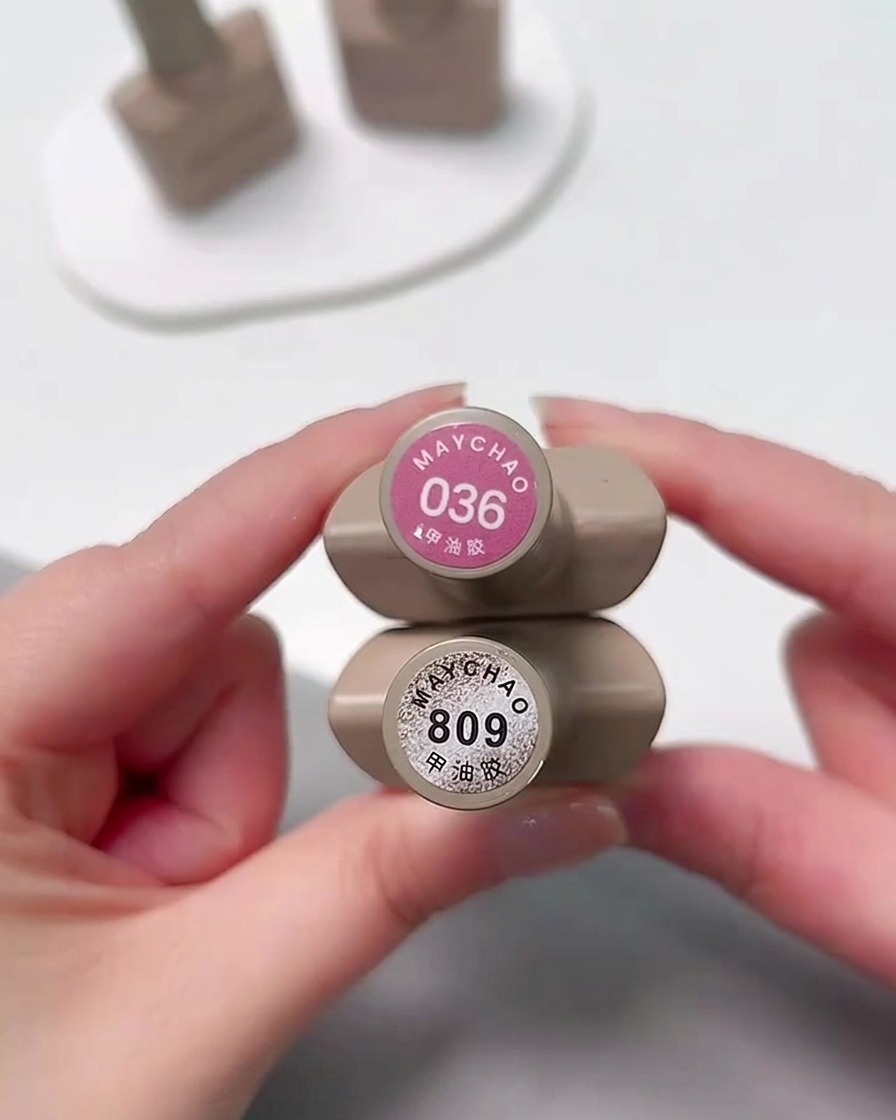 Zwei Fläschchen Gel-Nagellack, MAYCHAO Farbton 036 (Rosa) und 809 (silbernes Cat Eye), werden zusammen vor der Kamera gehalten.