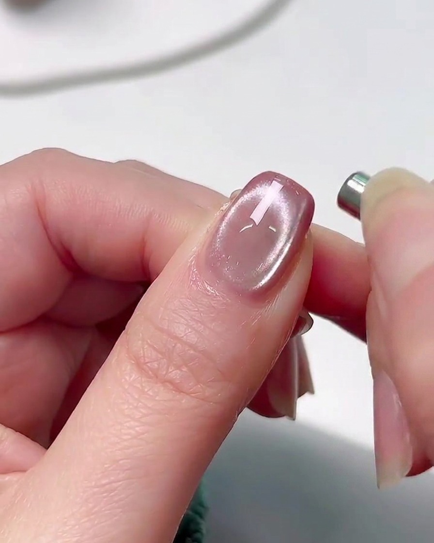Eine Hand wird in eine professionelle UV-Nagelaushärtungslampe gelegt, wobei ein sanftes rosa Leuchten die Finger beleuchtet.