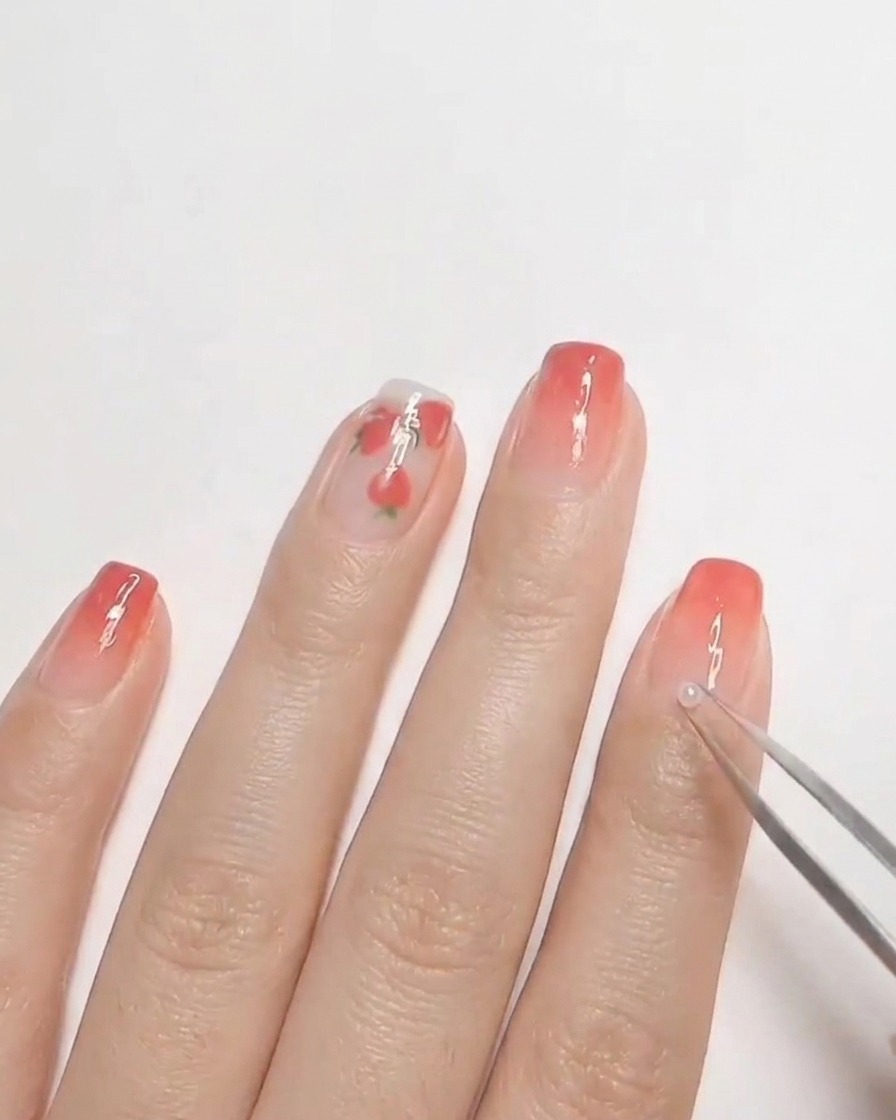 Eine Pinzette platziert eine kleine weiße Perle auf ungehärtetem Hard Gel auf einem Fingernagel.