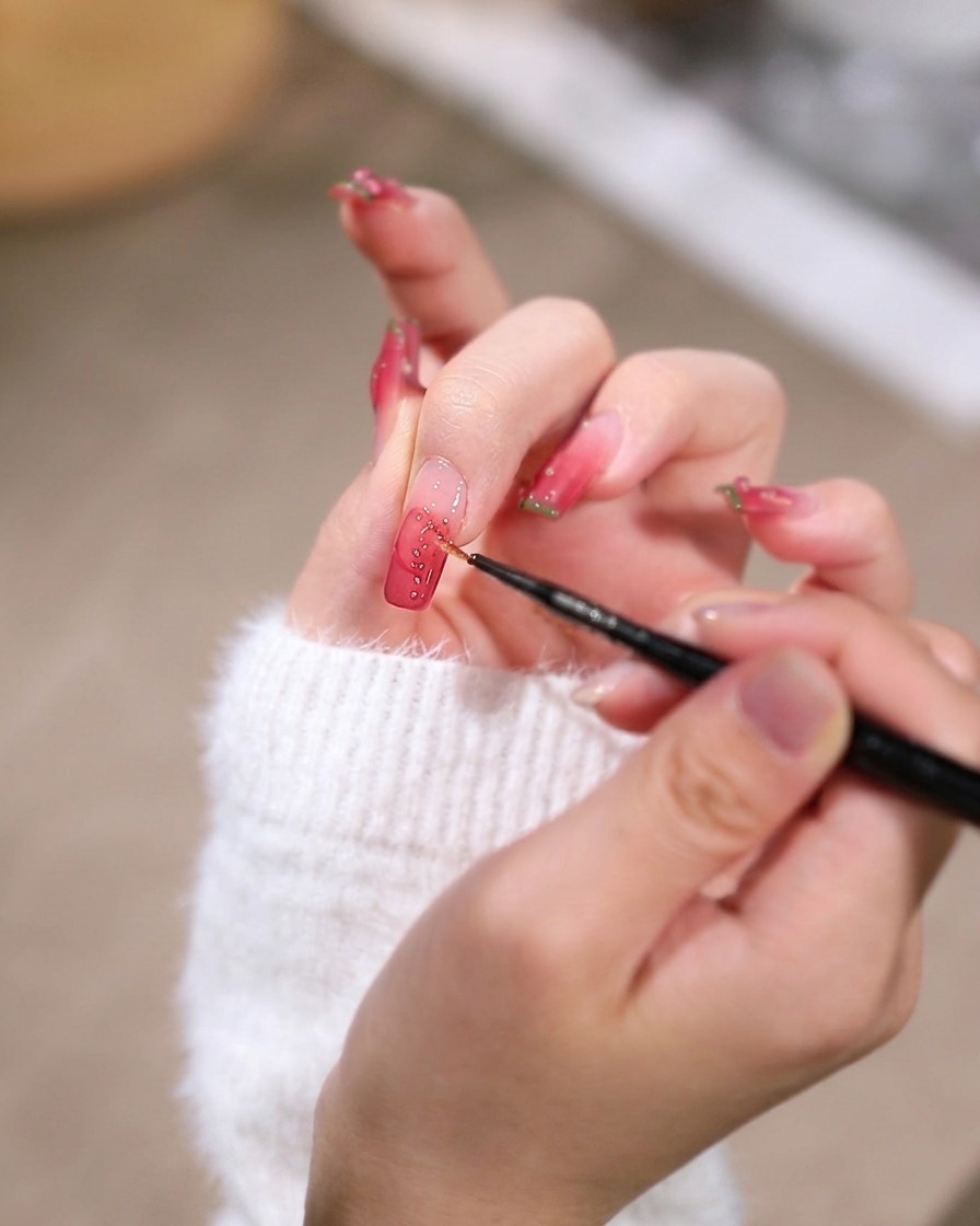 Eine Detailaufnahme eines feinen Werkzeugs platziert eine winzige Goldniete auf dem feuchten Gel nahe der Nagelbasis.