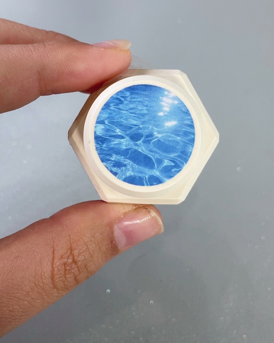 Eine Nahaufnahme eines Nagelpinsels, der ein klareres blaues Glasgel auf die Nagelspitze aufträgt.