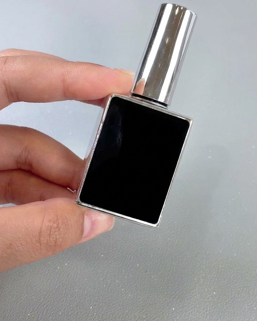 Eine quadratische schwarz-silberne Flasche Nagellack-Topcoat wird von Hand vor einem neutralen Hintergrund gehalten.