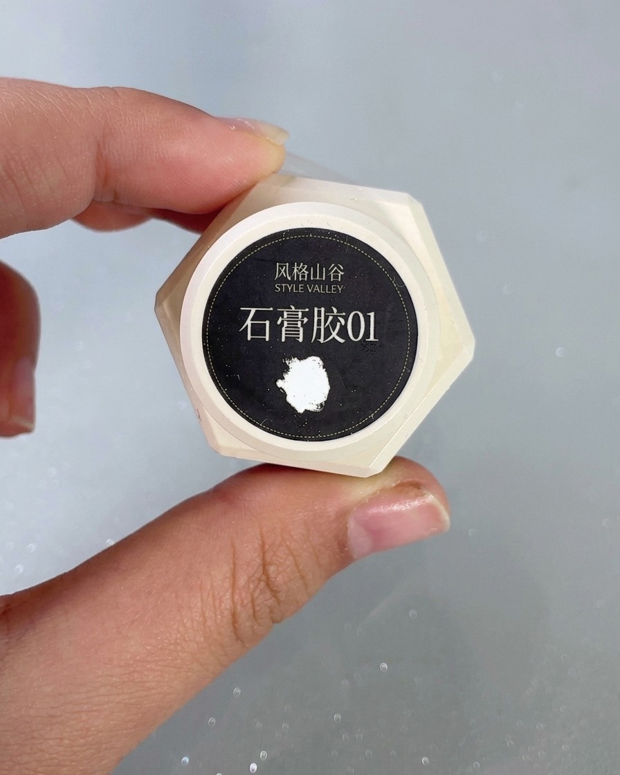 Ein feiner Nail-Art-Pinsel detailliert ein erhabenes, weißes Wellenmuster unter Verwendung von Pflastergel auf einem Nagel.