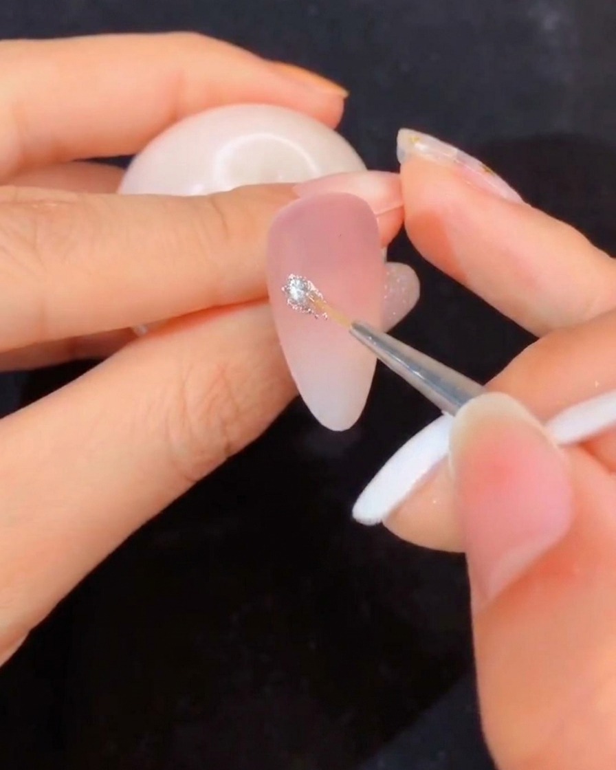 Eine Nahaufnahme eines Liner-Pinsels, der in einen offenen Tiegel mit klarem Modelliergel eintaucht.