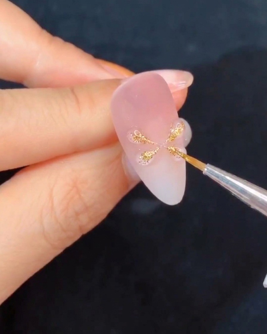Eine Hand hält einen Nagel unter eine Lampe zum Aushärten und hebt die frisch geformten Gel-Details hervor.