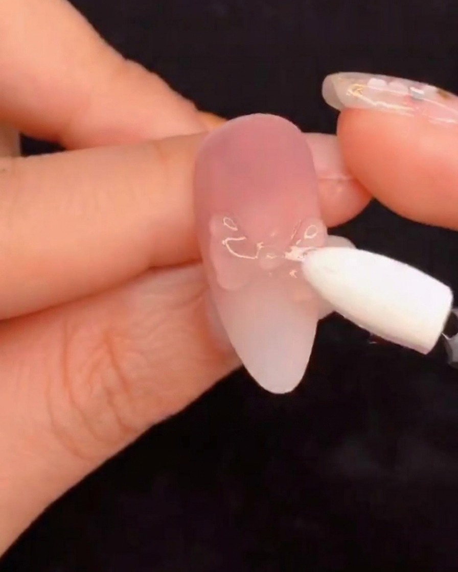 Ein Silikon-Schwamm-Applikator reibt Aurora-Pigmentpuder auf ein modelliertes Nageldesign.