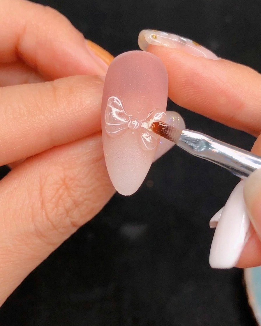 Das Auftragen des finalen Hochglanz-Top-Coats über das detaillierte Nageldesign.