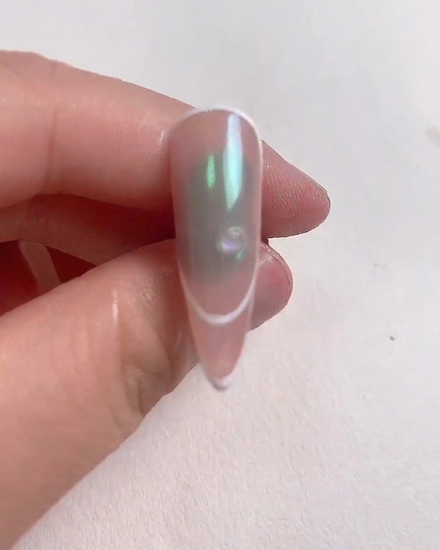 Ein kleiner, klarer Tropfen Aufbaugel wird in der Mitte eines dekorierten Nagels platziert.