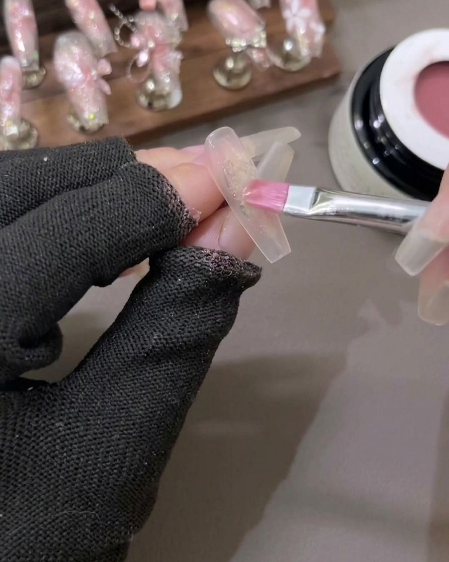 Ein Pinsel verblendet sanft eine transparente rote Gel-Farbe auf der Nagelmitte, um einen Verlaufeffekt zu erzielen.
