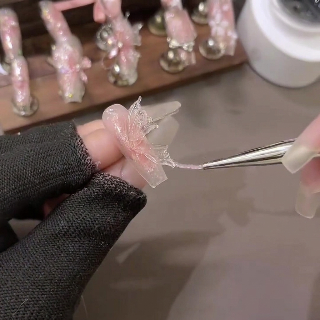 Ein Carving-Pinsel formt ein Dreieck aus PVC Soft Extension Gel auf Backpapier zu detaillierten Schmetterlingsflügeln.