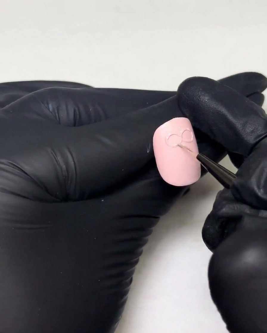 Beweumte Hände fügen eine dickere Schicht Aufbau-Gel über den bestehenden Schlaufen eines 3D-Schleifendesigns auf einem Nagel hinzu.