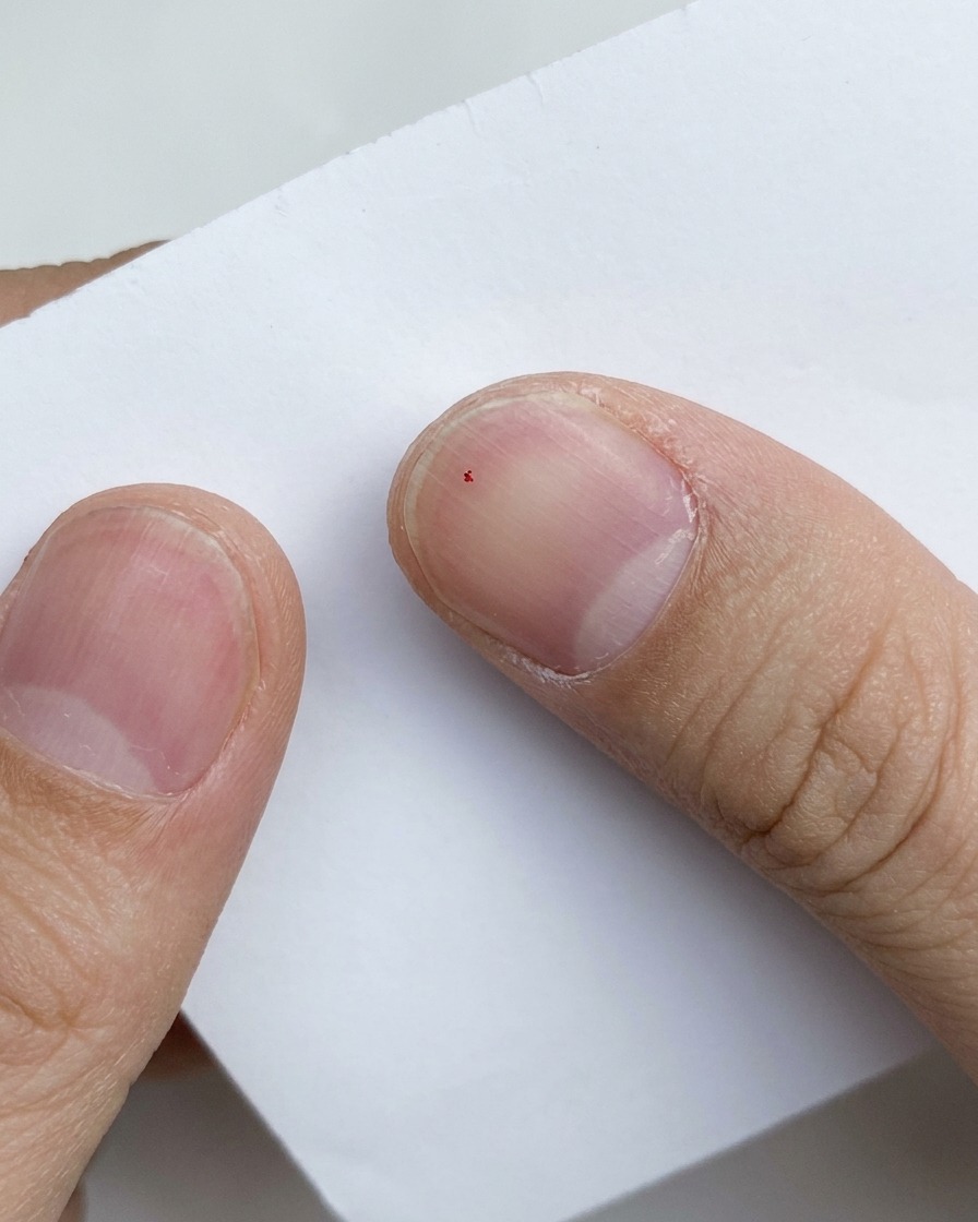 Nahaufnahme von lila Glitzerpartikeln, die auf einem weißen Papieruntergrund in Gel gemischt werden.